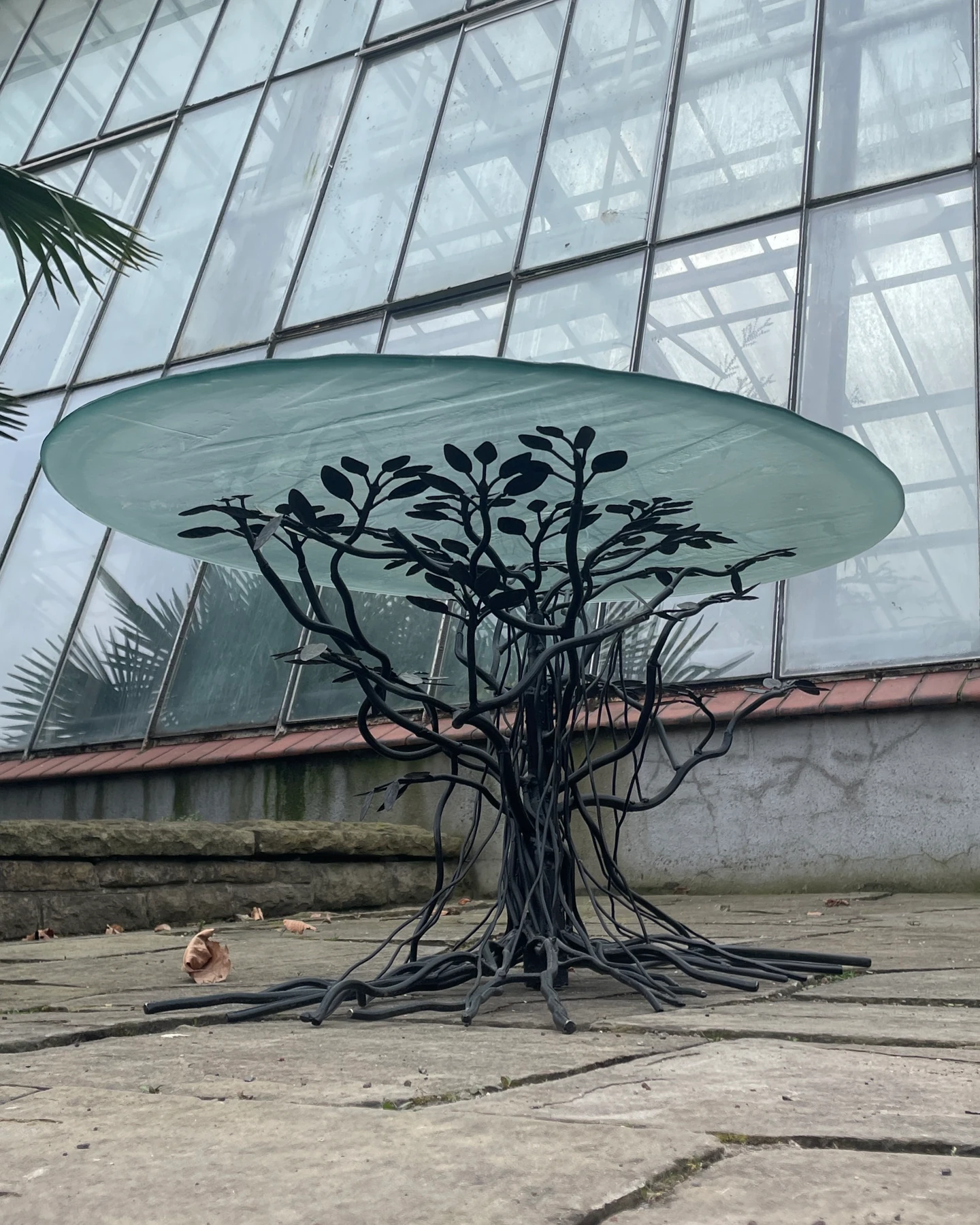 A sculptural table against the greenhouse.