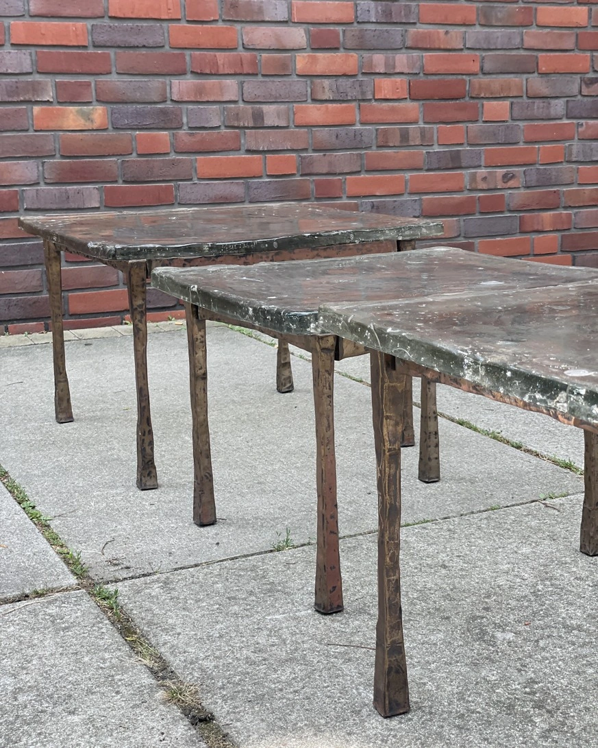 Slender forged frames beneath cast-glass tabletops.